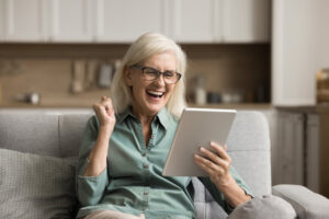 Glückliche Frau mit Tablet zu Hause auf dem Sofa